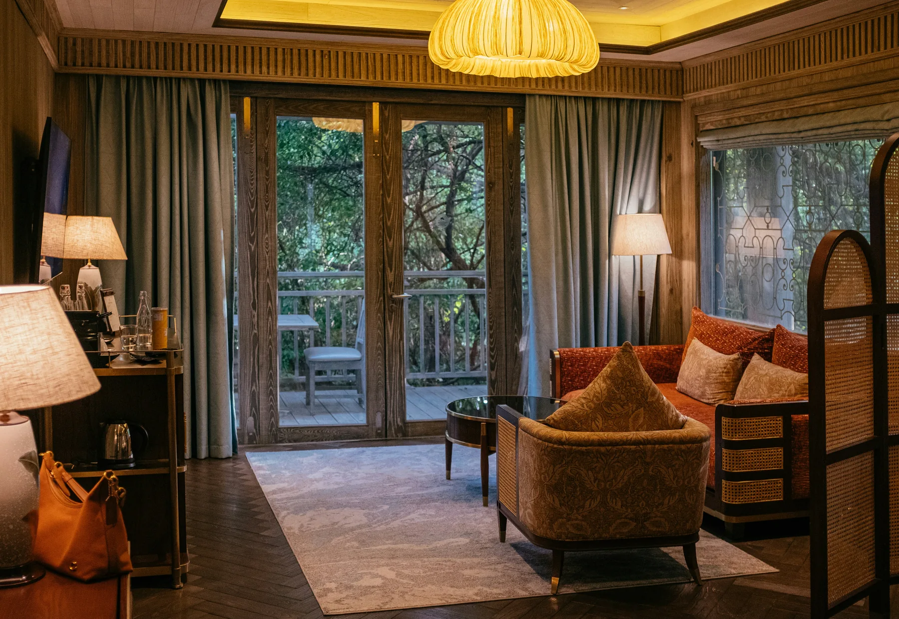 Warm hospitality room interior opening to a tree-lined balcony