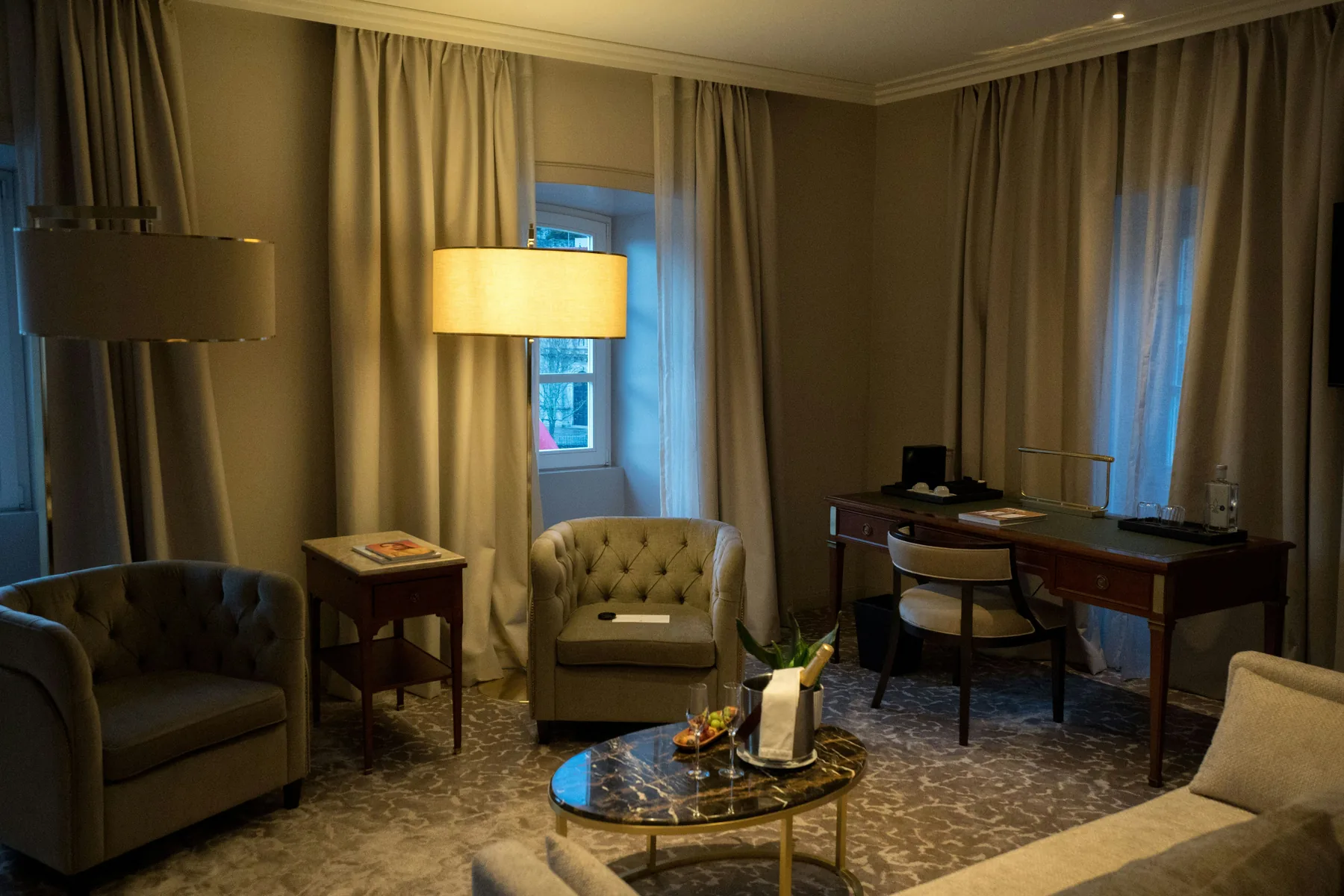 Well-lit hotel room interior with lounge seating and a writing desk